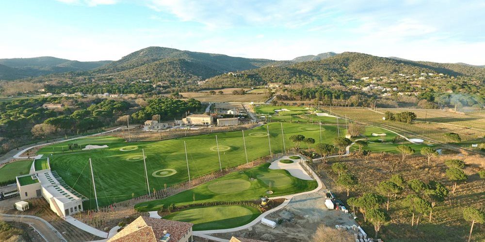 Aerial view of a synthetic grass golf course surrounded by hills
