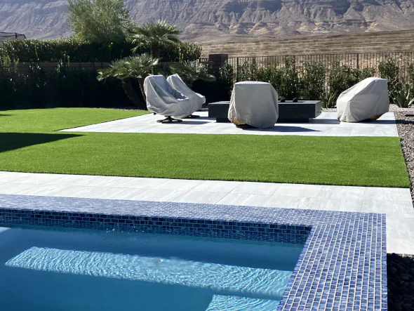Modern backyard with poolside patio and seating area bordered by lush artificial grass lawn for a clean, low-maintenance outdoor living space.