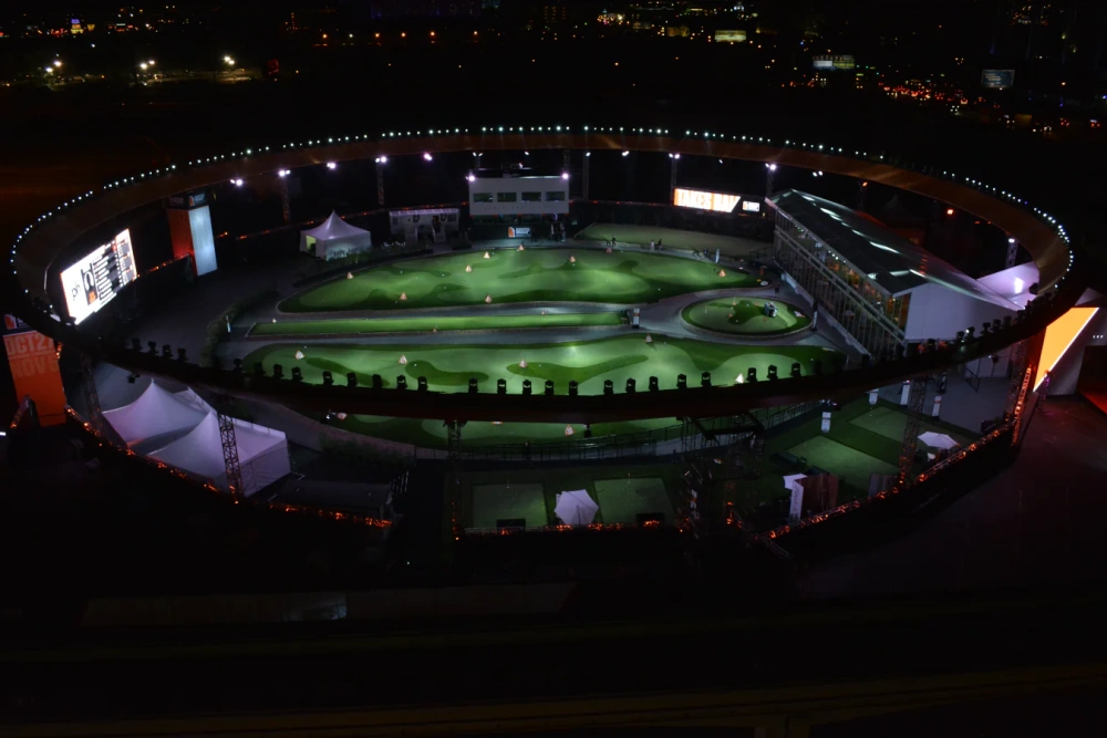 Large illuminated golf facility featuring professional artificial turf installation with contoured greens, target areas, and durable synthetic surfaces for nighttime play and training.