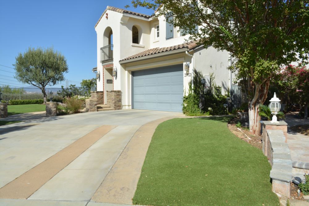 Front yard synthetic turf installation with Mediterranean style home and circular driveway