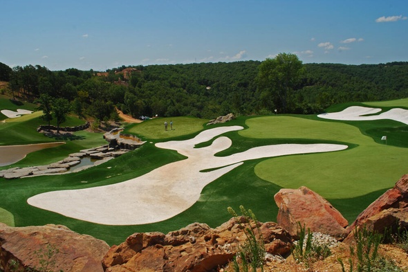 lush green synthetic grass golf course with white sand bunkers and blue sky