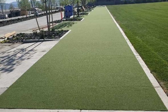 Outdoor tee line consisting of one continuous green synthetic grass strip surrounded by trees
