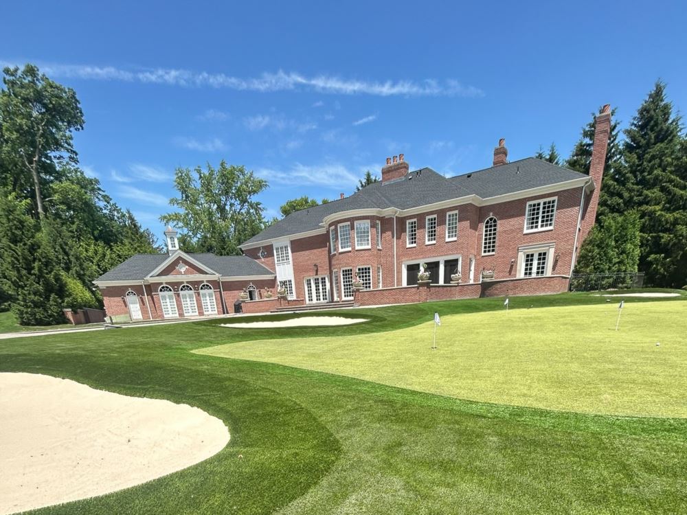 Artificial turf putting green in front of a 2 story house